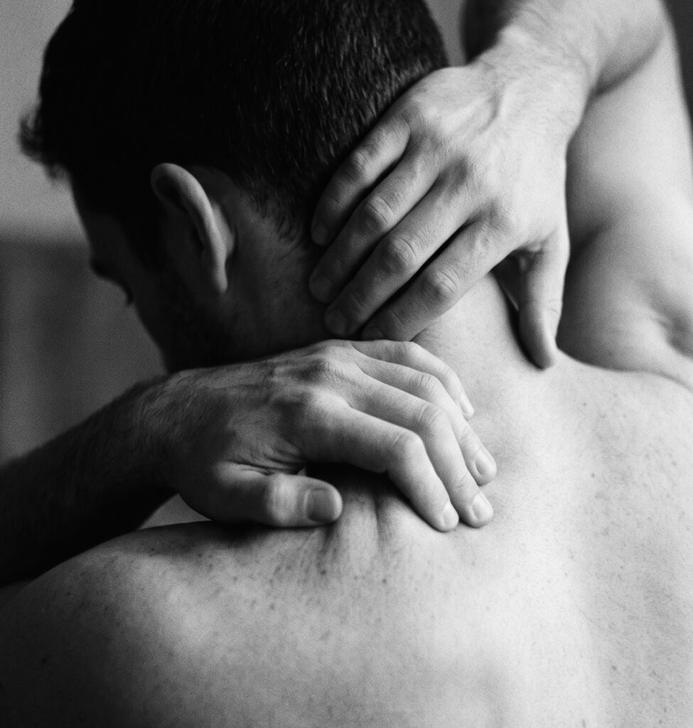 Manos de la fisioterapeuta trabajando la nuca y el hombro de un hombre